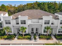 Beautiful townhome exterior with manicured landscaping, stone accents, and palm trees at 17230 Blessing Dr, Clermont, FL 34714