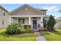 Charming home featuring a blue front door, manicured lawn, and lovely landscaping at 17985 Adrift Rd, Winter Garden, FL 34787