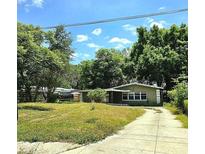 Cozy single-story home with a driveway and a lush green lawn, shaded by mature trees at 1914 Geigel Ave, Orlando, FL 32806