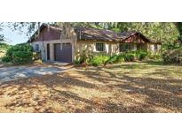 Charming single-story home featuring a brick facade, attached garage, and mature landscaping at 36208 Micro Racetrack Rd, Fruitland Park, FL 34731