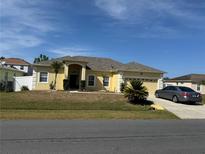 Charming yellow single-story home with well-manicured lawn and driveway with parked car at 708 Pincon Ln, Kissimmee, FL 34759