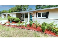 Charming home with a tidy lawn, a colorful flowerbed, and a bright blue front door at 735 Baltimore Dr, Orlando, FL 32810