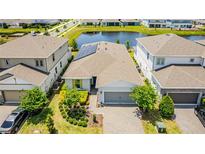 An aerial view of the house with solar panels, landscaping, and a nearby pond at 13864 Destin Beach Ln, Orlando, FL 32827