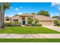 Charming single-story home features a well-manicured lawn, a blue front door, and attached two-car garage at 4119 Pecan Ln, Orlando, FL 32812