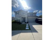 Charming two-story home with blue accents, landscaped lawn, and a two car garage at 5006 Vellacito Way, Davenport, FL 33897