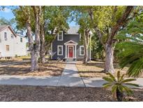 Beautiful gray home with red door framed by mature trees and a charming walkway at 821 E Lemon Ave, Eustis, FL 32726