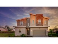 Beautiful two-story home featuring stone accents, gray exterior paint, and a well-manicured lawn at 901 Ocean Course Ave, Davenport, FL 33896