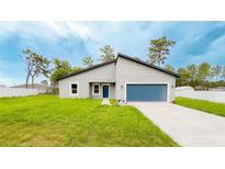 Charming single-story home featuring a blue garage door, well-kept lawn, and a modern roof design at 14957 Sw 63Rd Court Rd, Ocala, FL 34473
