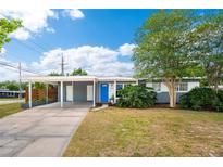 Charming single-story home featuring a bright blue door, covered parking, and mature landscaping at 3520 Sebring Ave, Orlando, FL 32806