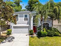Two story home with well manicured lawn, landscaping, and red front door at 4027 Lakeside Reserve Ct, Orlando, FL 32810