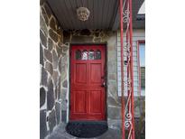Inviting stone-clad entrance with a striking red door and decorative security door showcasing curb appeal at 7506 Mott Ave, Orlando, FL 32810