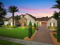 Charming home boasts lush landscaping, a brick driveway, barrel tile roof and a stone-accented façade at 11502 Waterstone Loop Dr, Windermere, FL 34786