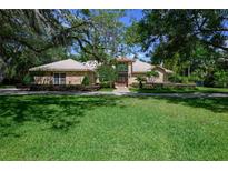 Charming brick home with mature trees, manicured landscaping, and a welcoming front entrance at 725 Bear Creek Cir, Winter Springs, FL 32708