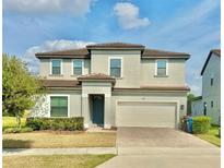 Two-story home featuring neutral paint, attached two-car garage, well-maintained landscaping and a brick driveway at 144 Angelas Ave, Haines City, FL 33844