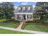 Inviting yellow home showcasing a manicured lawn, brick path and white pillared porch beneath a dark roof at 1448 Conway Isle Cir, Belle Isle, FL 32809