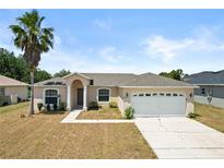 Charming single-story home featuring a two-car garage, manicured lawn, and a welcoming front entrance at 15 Sawfish Ln, Kissimmee, FL 34759