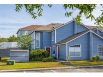Charming two-story townhouse with blue siding, manicured lawn, and convenient parking spaces at 242 Coco Plum Dr, Davenport, FL 33897