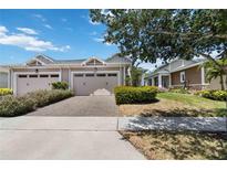 Charming tan home featuring a two-car garage and a beautifully paved driveway and walkway at 2423 Datura Loop, St Cloud, FL 34772