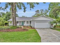 Charming single-story home with a well-manicured lawn, mature tree, and an attached two-car garage at 2610 Cloudcroft Dr, Apopka, FL 32703