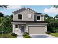 Charming two-story home with gray siding, stone accents, manicured lawn, and a two-car garage at 3824 Bluethread Way, Poinciana, FL 34759