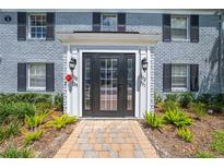 Inviting front entrance featuring a black door, brick walkway, and well-maintained landscaping at 130 Lewfield Cir # 130, Winter Park, FL 32792