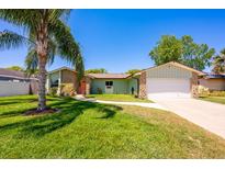 Charming single-story home with a well-manicured lawn, stone accents, and a mature palm tree at 208 Madeira Ave, Orlando, FL 32825