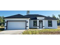 Charming single-story home featuring a two-car garage, white exterior, and black trim at 273 Marion Oaks Golf Rd, Ocala, FL 34473