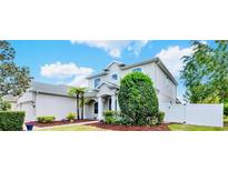 Charming two-story home with well-manicured landscaping, mulch beds, and a white fence at 955 Holly Springs Ter, Oviedo, FL 32765