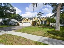 Charming yellow home with a three-car garage, lush lawn and mature landscaping at 1006 Hanging Vine Pt, Longwood, FL 32750