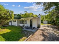 Charming one-story white home featuring a chimney and a small, detached garage, surrounded by lush greenery at 2647 S Myrtle Ave, Sanford, FL 32773