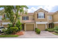 Charming townhome featuring a brick driveway, tile roof, and lush landscaping at 3567 Shallot Dr # 103, Orlando, FL 32835