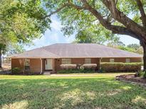 Charming brick home with mature trees, landscaped front yard, and inviting entryway at 7540 Lake Marsha Dr, Orlando, FL 32819