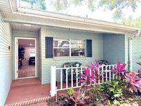 Charming covered front porch with brick detail, a small garden, and seating area at 9490 Sw 85Th Ave # E, Ocala, FL 34481