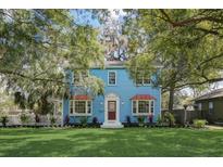Charming blue two-story home with manicured lawn and beautiful mature trees creating curb appeal at 1000 Pennsylvania Ave, Lakeland, FL 33803