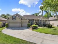 Charming home featuring a three car garage, beautiful landscaping, and a curved driveway at 14315 Letham Grange Ct, Orlando, FL 32828