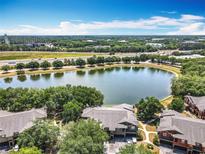 An aerial view showcases lakeside condos with lush trees, water view, and easy access to the highway at 163 Villa Di Este Ter # 105, Lake Mary, FL 32746