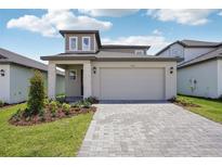 Charming two-story home with a well-manicured lawn and a two-car garage with brick paver driveway at 1904 Archer Dr, Minneola, FL 34715
