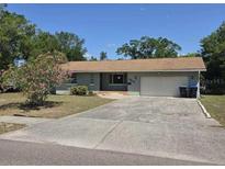 Ranch style home with a light colored exterior, an attached garage, and mature landscaping at 2523 Falkner Rd, Orlando, FL 32810