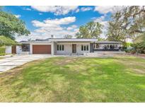 Contemporary home boasts a modern design, featuring a well-manicured lawn, sleek lines and a stylish wood garage door at 2525 Venetian Way, Winter Park, FL 32789