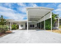 Bright white home featuring a covered carport, mature landscaping, and blue skies at 367 Par Pines Blvd, Davenport, FL 33837