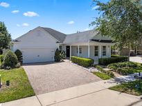 Charming single-story home featuring a manicured lawn, brick driveway, and attached two-car garage at 11407 Wakeworth St, Orlando, FL 32836
