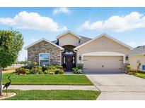 Charming single-story home with a stone facade, landscaped yard, and a two-car garage at 1703 Daystar Dr, Haines City, FL 33844