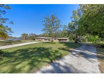 Charming exterior of home with mature trees, long driveway, and lush green lawn at 20 Lido Rd, Winter Springs, FL 32708