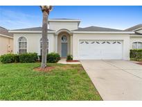 Charming single-story home with a well-manicured lawn and a two-car garage on a sunny day at 2263 Wyndham Palms Way, Kissimmee, FL 34747