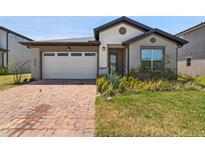 Charming single-story home featuring a brick driveway, a two-car garage, and well-maintained landscaping at 3128 Oxbow Ct, Harmony, FL 34773