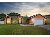 Charming single-story home with a well-maintained lawn, mature landscaping, and an attached two-car garage at 4051 Eagle Feather Dr, Orlando, FL 32829