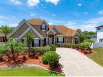 Beautiful tan two-story home with a well manicured lawn and a circular driveway at 5062 Otters Den Trl, Sanford, FL 32771