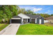 Charming single Gathering home features a manicured lawn, gray accent walls, and a 2-car garage at 7025 Hiawassee Oak Dr, Orlando, FL 32818