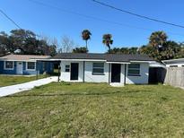 Charming white home with dark doors, a covered patio, and a freshly painted driveway at 73 Brooks Dr, Ormond Beach, FL 32176