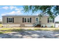 Charming single-story home with a front porch, neutral siding, and black shutters against a backdrop of blue skies at 8218 Pine Island Rd, Clermont, FL 34711